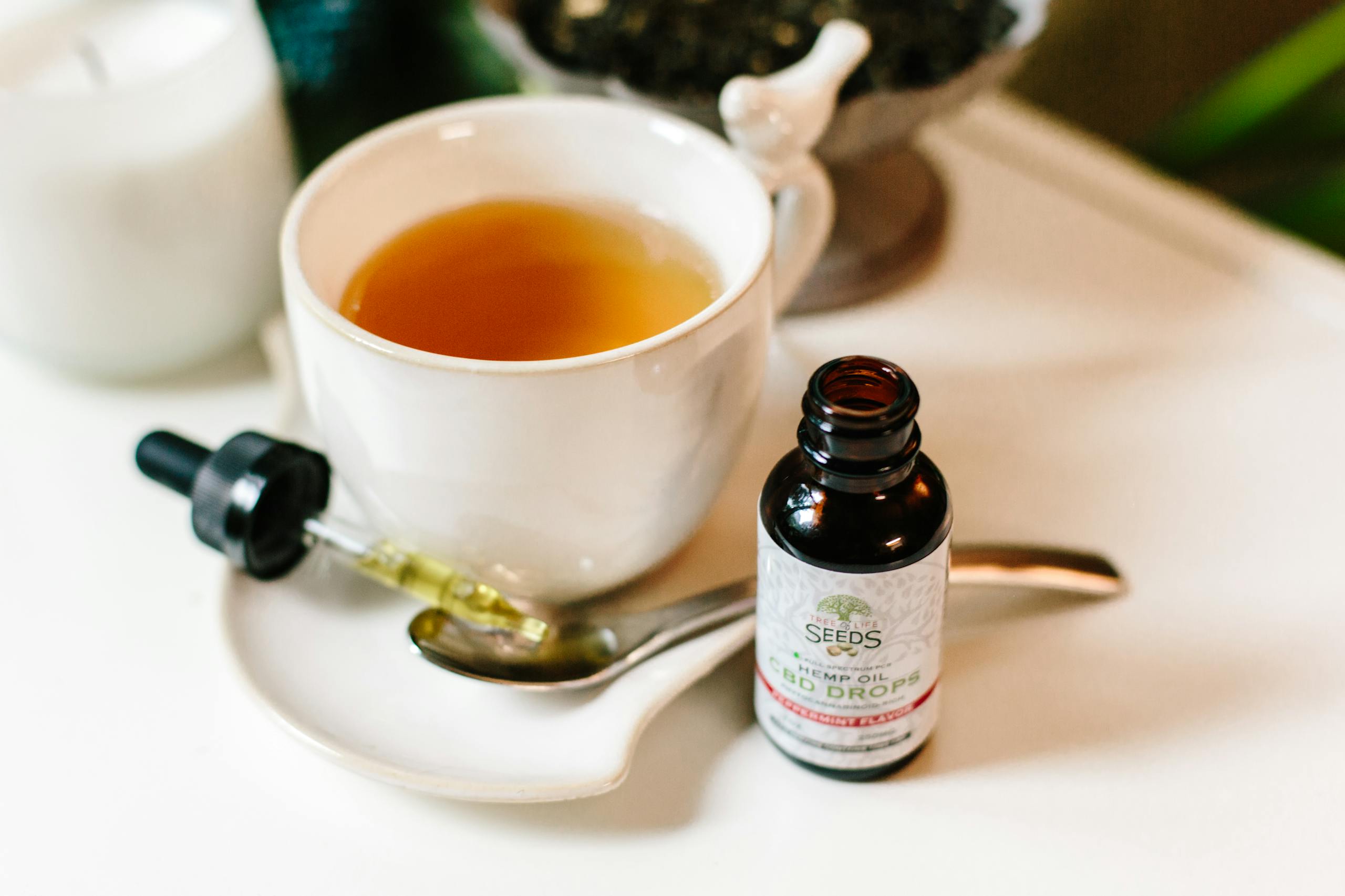 A calming setup featuring CBD oil dropper and hot tea in a cozy indoor setting.