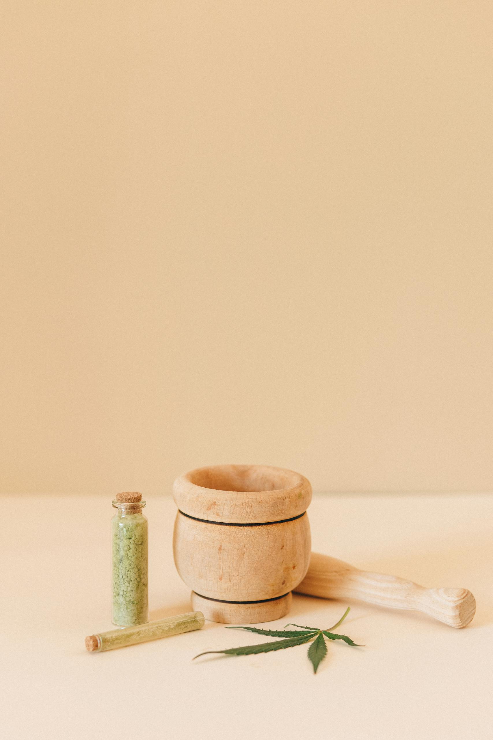 Aesthetic setup of herbal remedy tools with a mortar, pestle, and cannabis leaf.