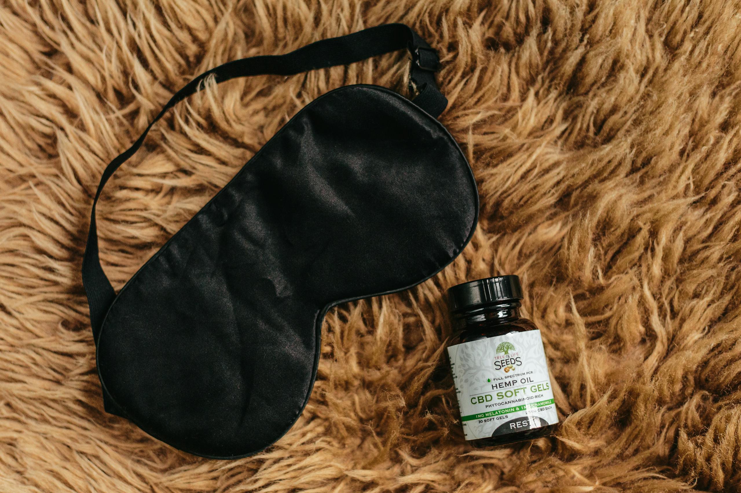 CBD soft gels and black eye mask laid on brown fur promoting relaxation and sleep.